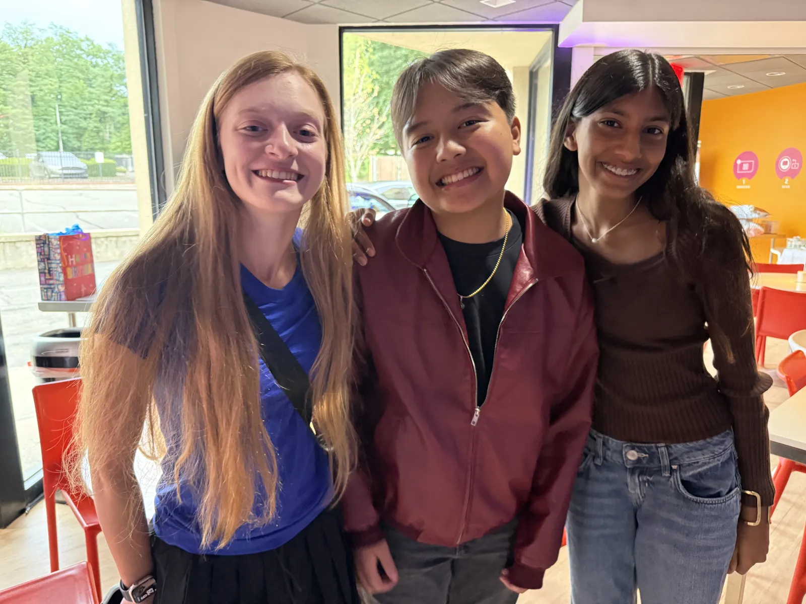 Three friends smiling together at Genius Gems Millburn