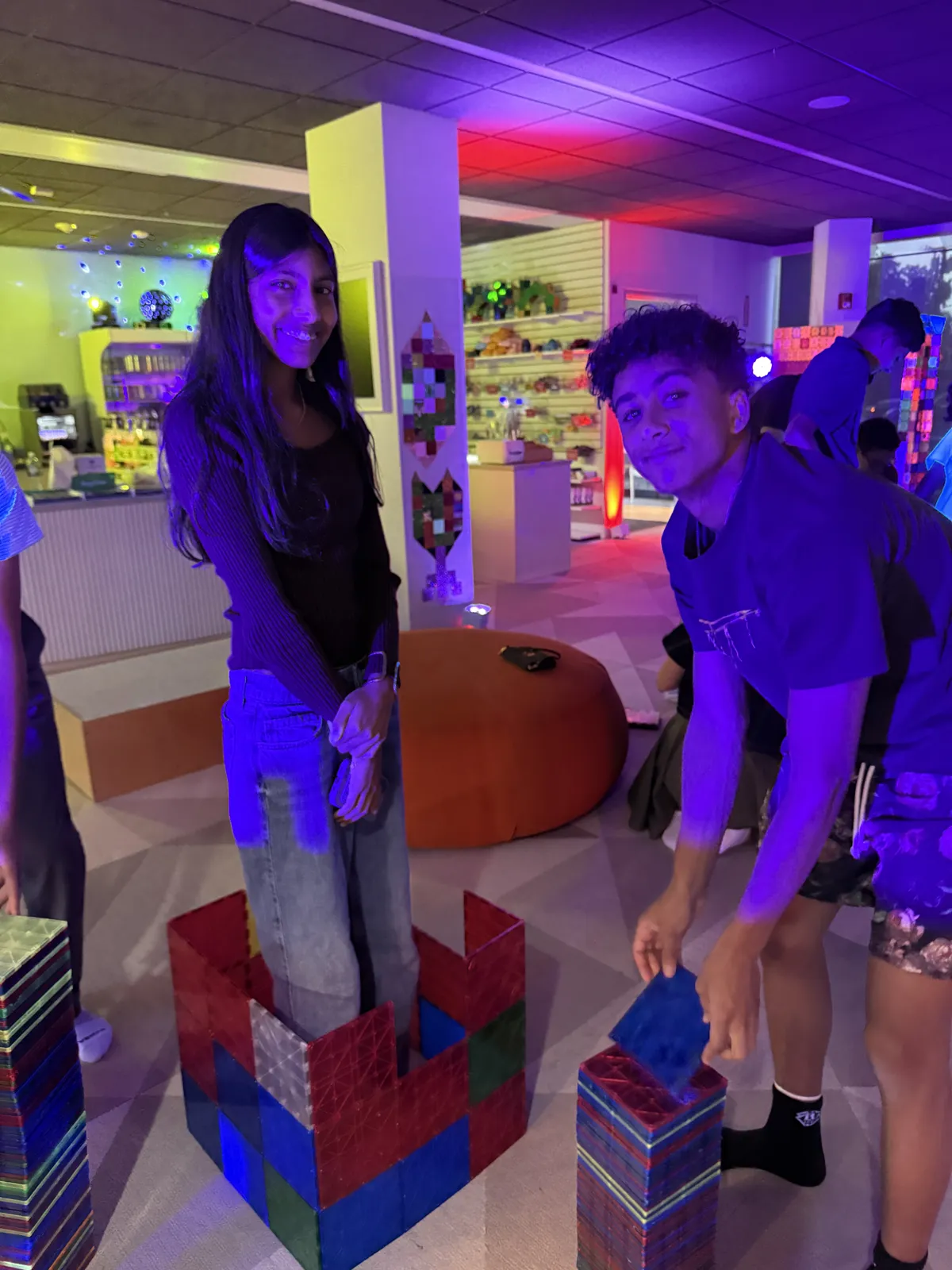 Two teens building a tall magnetic tile tower