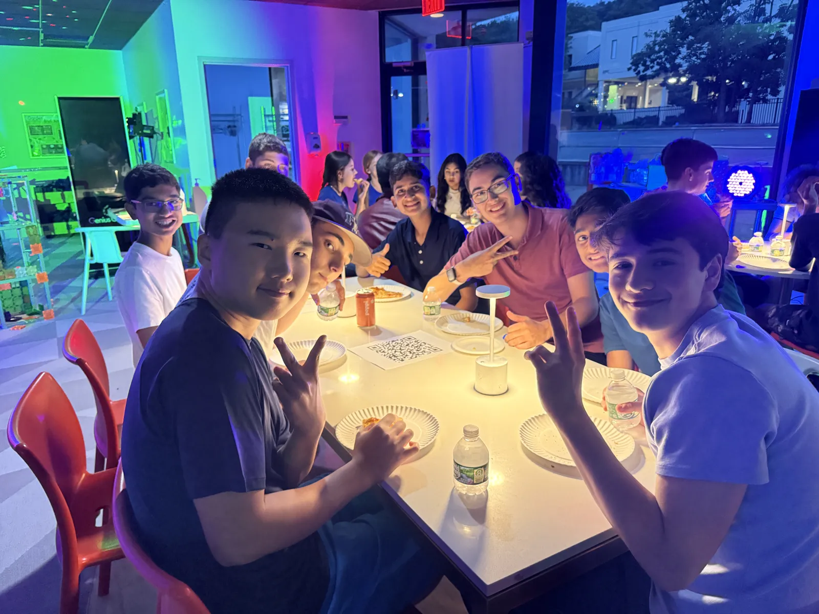 Teens at candlelit tables under purple and pink lights at an After Dark night in Millburn